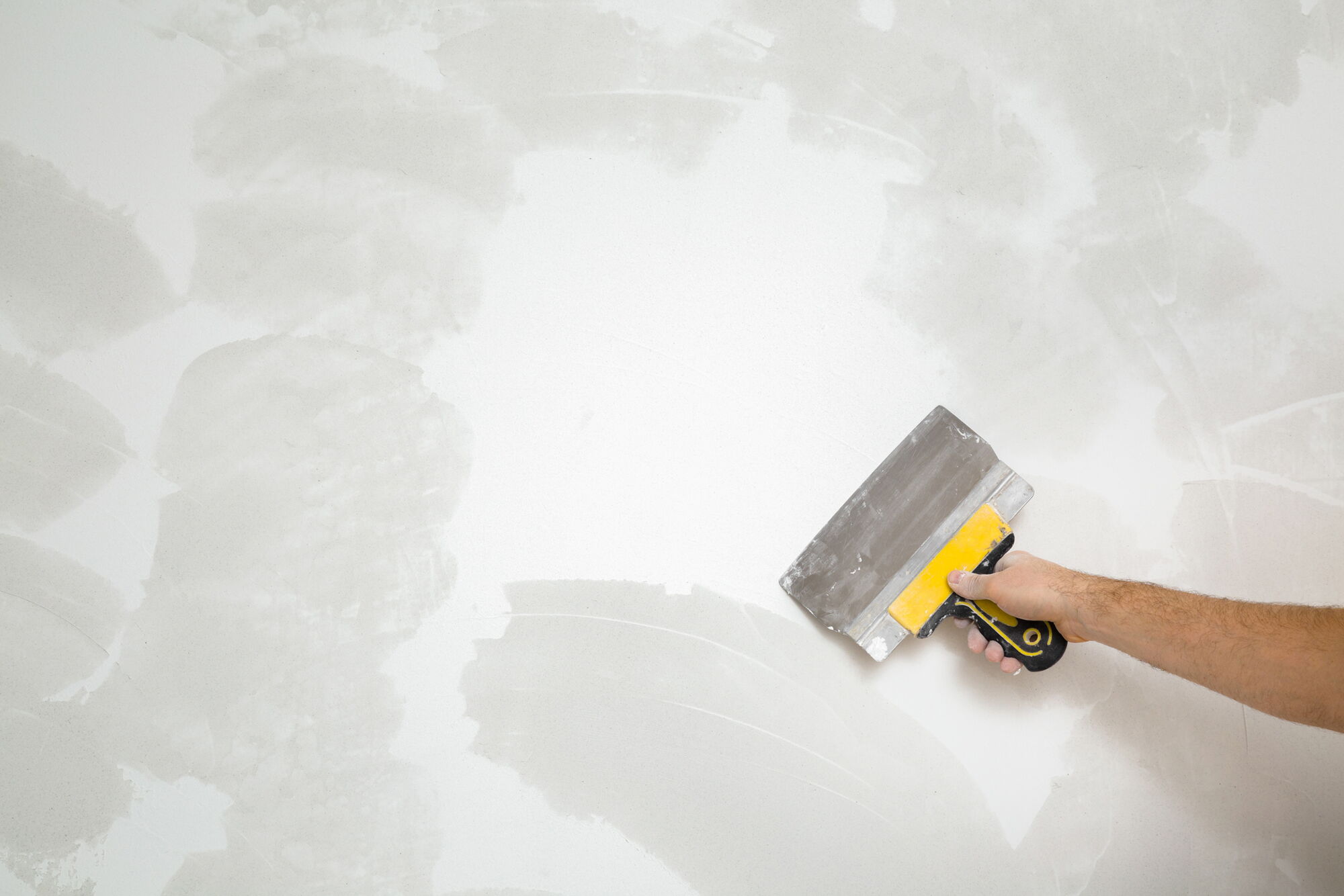 Handwerker spachtelt eine Wand nach einer Feuchtesanierung aufgrund eines Schimmelschadens